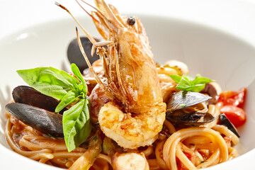 Italian dish - seafood linguine isolated on white background. Pasta with prawn, mussels, octopus, ...