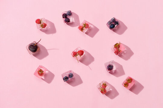 fresh berries with mint in ice cubes on pink background top view