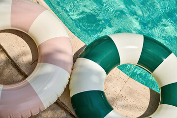 Multicolored swimming tubes on beige tiled poolside