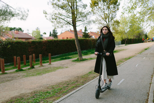 Woman  riding an e-scooter in bike lane. Sustainable city concept.
