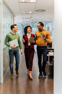 Cheerful multiethnic colleagues walking in office