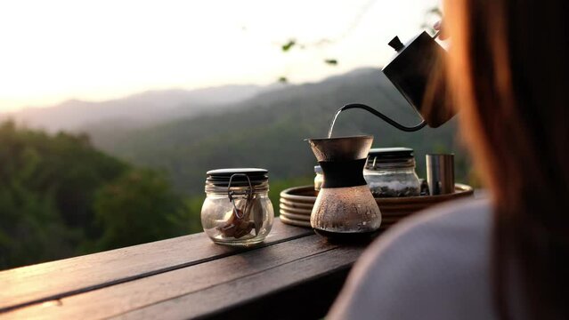A woman making drip coffee with a beautiful nature view in the morning