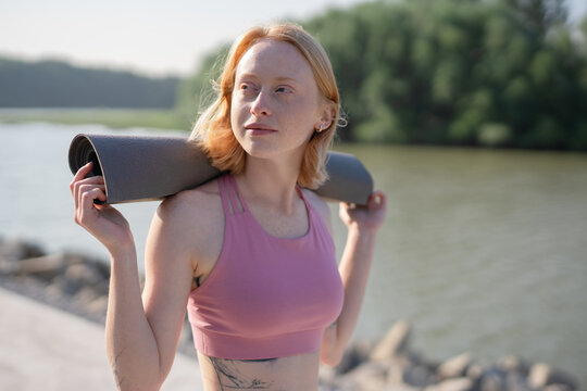 ginger fitness woman posing in the street with yoga mat