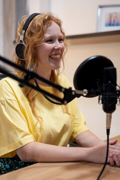 Young lady taking notes and recording radio podcast