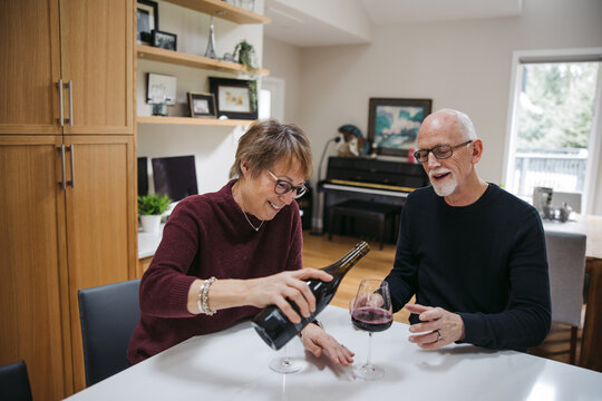 Mature couple pouring red wine inside.