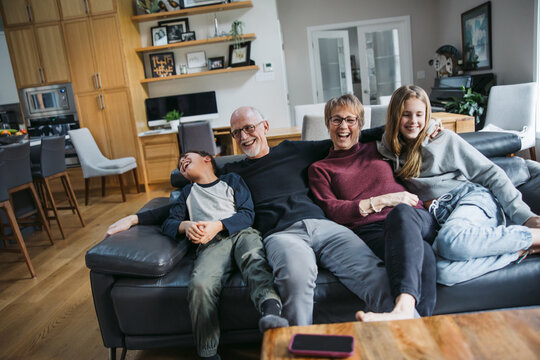 Grandparents and grandkids cudding on the couch.