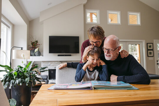 Grandparents and kid looking at photobook together.