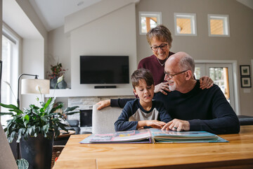Grandparents and kid looking at photobook together.