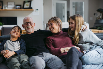 Grandparents and grandkids cudding on the couch.
