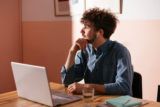 Thoughtful student sitting with laptop in library