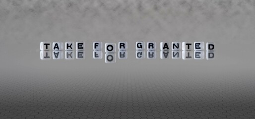 take for granted word or concept represented by black and white letter cubes on a grey horizon...