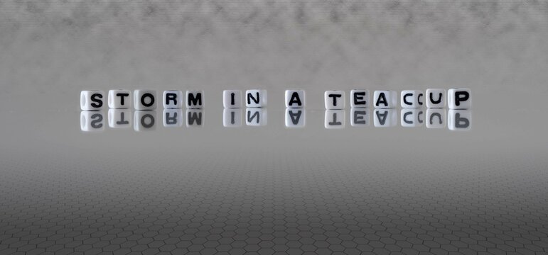 storm in a teacup word or concept represented by black and white letter cubes on a grey horizon background stretching to infinity