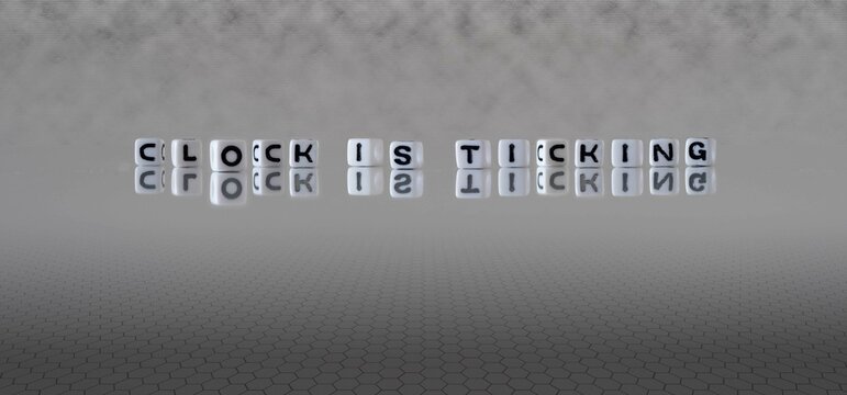 clock is ticking word or concept represented by black and white letter cubes on a grey horizon background stretching to infinity