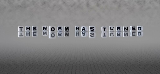 the worm has turned word or concept represented by black and white letter cubes on a grey horizon background stretching to infinity