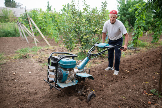 Man With Cultivator Preparing Land For Planting