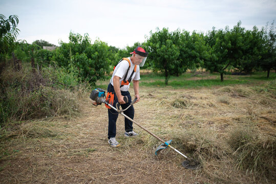 Farmer Removing Weeds With An Electric Mower