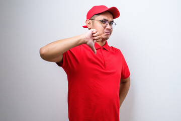 Disappointed asian delivery man in red t-shirt and cap express dislike and bad attitude