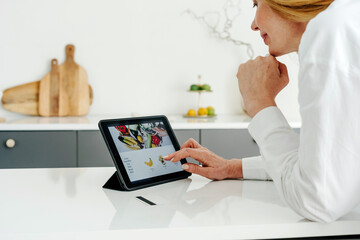 Woman making online purchases in food shop on tablet
