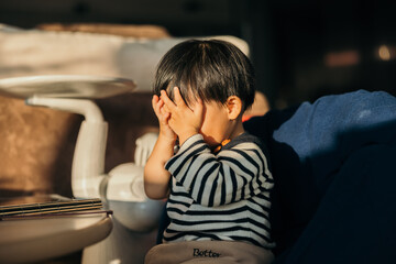 Baby boy covering eyes in the sun