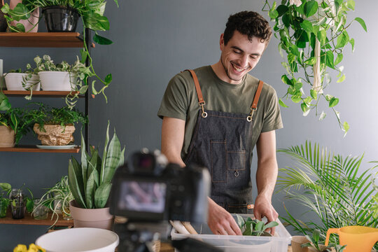 Smiling Man Repotting Pothos In Bigger Vase And Filming The Process