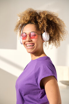 Beautiful afro woman listening to music with white headphones