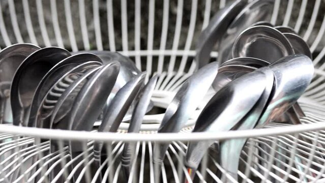 Aluminum spoons are dried in a grate drip tray swaying on the wall