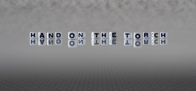 hand on the torch word or concept represented by black and white letter cubes on a grey horizon background stretching to infinity