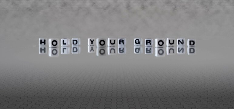 hold your ground word or concept represented by black and white letter cubes on a grey horizon background stretching to infinity
