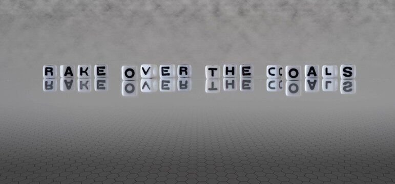 rake over the coals word or concept represented by black and white letter cubes on a grey horizon background stretching to infinity