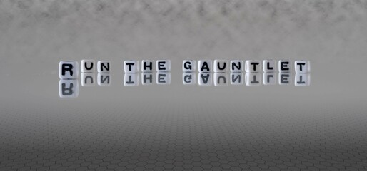 run the gauntlet word or concept represented by black and white letter cubes on a grey horizon...