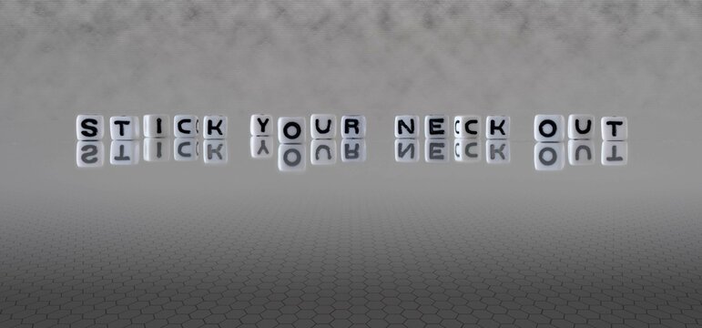 stick your neck out word or concept represented by black and white letter cubes on a grey horizon background stretching to infinity