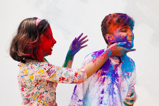 Brother and sister playing holi together with color powder