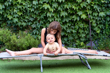 Girl hugging baby boy and kissing head on camp bed