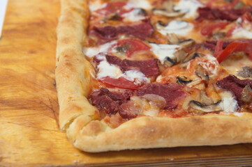 Freshly baked pizza with various herbs on a wooden stand.