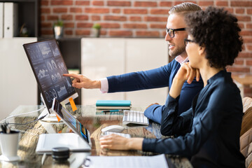 Two Stock Market Brokers Discussing Graphs On Computer