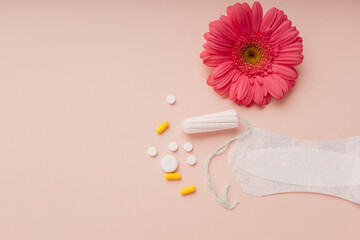 Fototapeta na wymiar Women menstrual cycle concept. Sanitary pad, pills and tampon isolated on pink background with flower