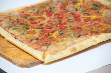 Freshly baked pizza with various herbs on a wooden stand.
