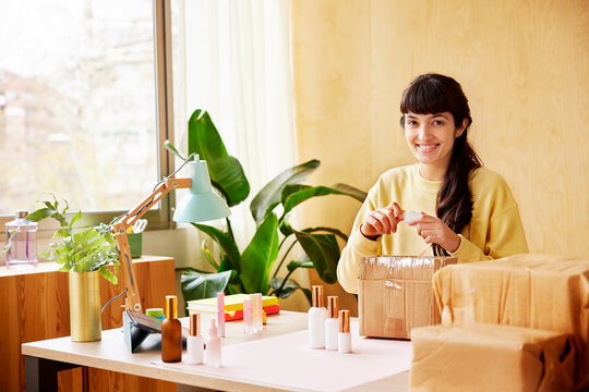 Friendly female entrepreneur packing cosmetic products