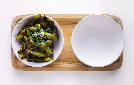 Plate with grilled edamame in bowl on table