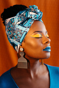 Woman with African print head band and creative makeup over orange 