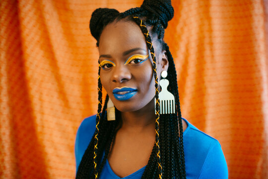 Woman with braided hair and creative colorful makeup looking at camera