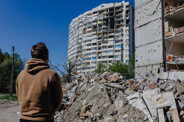 Chernihiv Ukraine 2022: a guy looks at the ruins after an air strike. Rear view. The building was...