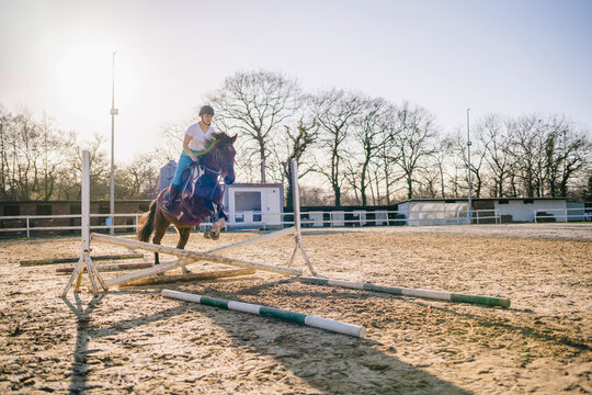 Woman on horse jumping over hurdle