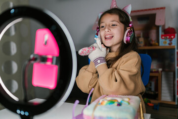 Merry girl shooting video with toy