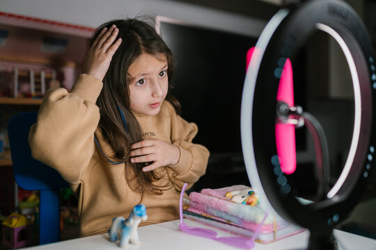 Little blogger touching hair during before recording