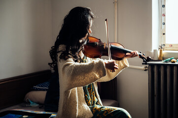An asian young woman playing violin at home