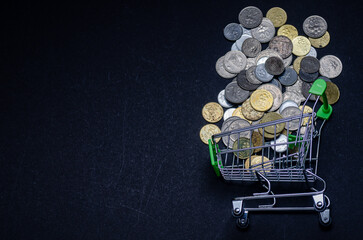 A finance concept photo using trolley and coins over the black background