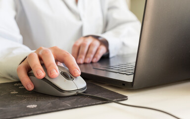 A girl's hand on a computer mouse. The concept of remote work. Close-up. Selective focus