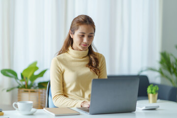 Fototapeta premium Portrait of young Asian business woman using laptop computer at home office.