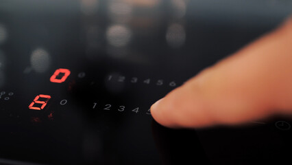 Close up of man setting temperature control on hob